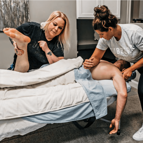 Megan Sanders of Subzero Wellness and her assistant performing a massage on a patient to relieve discomfort.