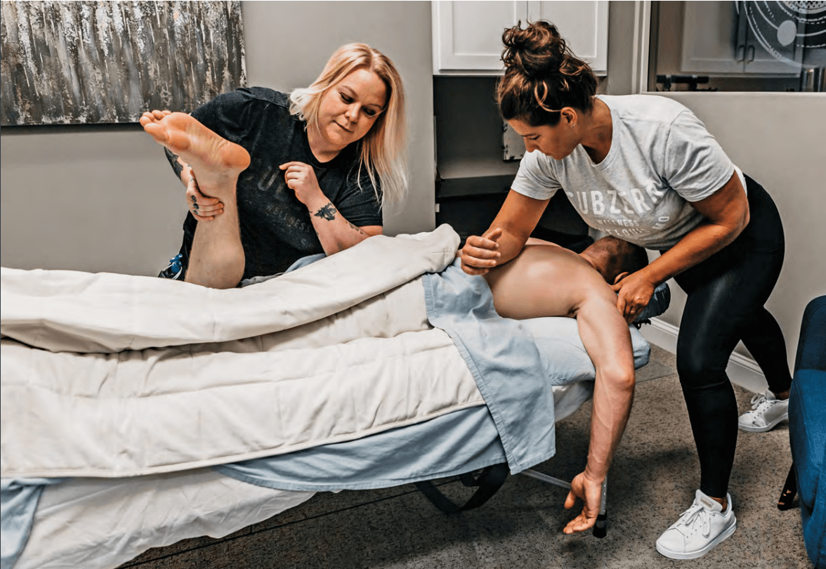 Megan Sanders of Subzero Wellness and her assistant performing a massage on a patient to relieve discomfort.